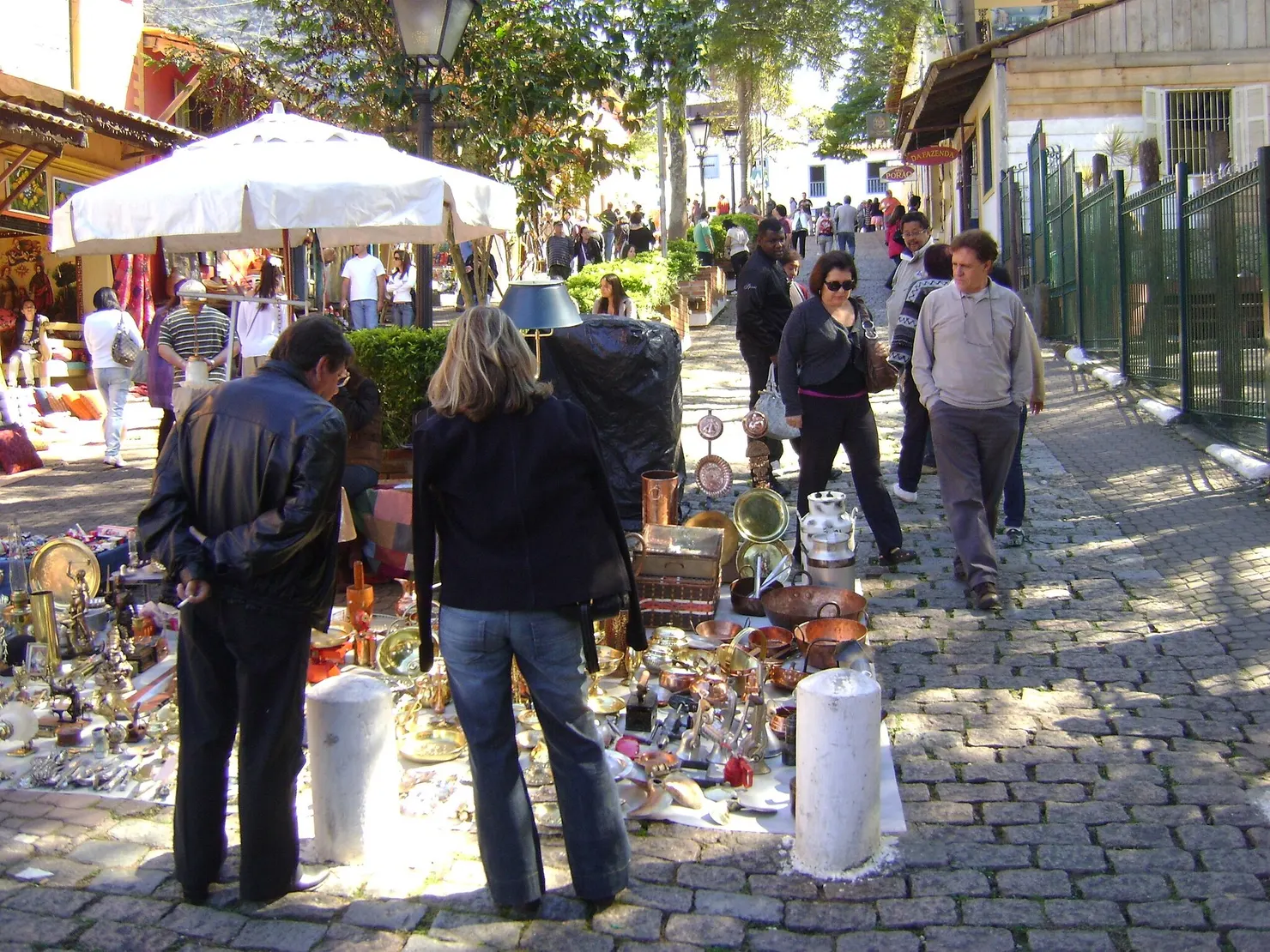 pessoas olhando itens da feira expostos sob tapetes no chão